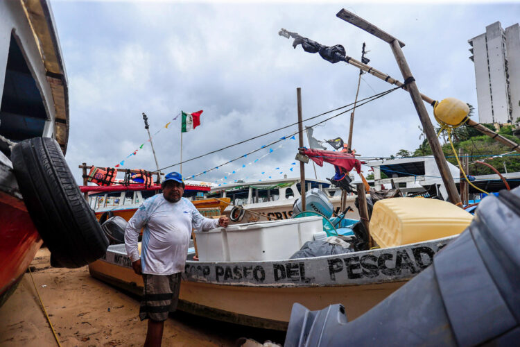 Un pescador aguarda junto a una embarcación afuera del agua tras las amenazas de lluvias por el paso del ciclón Trudy que se intensificó a huracán categoría 1 este jueves, en el balneario de Acapulco (México). EFE/David Guzmán